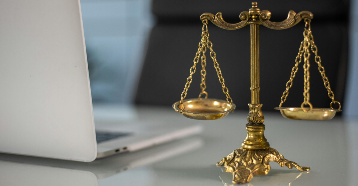 Golden justice scales on a desk beside a laptop, symbolizing law and balance.