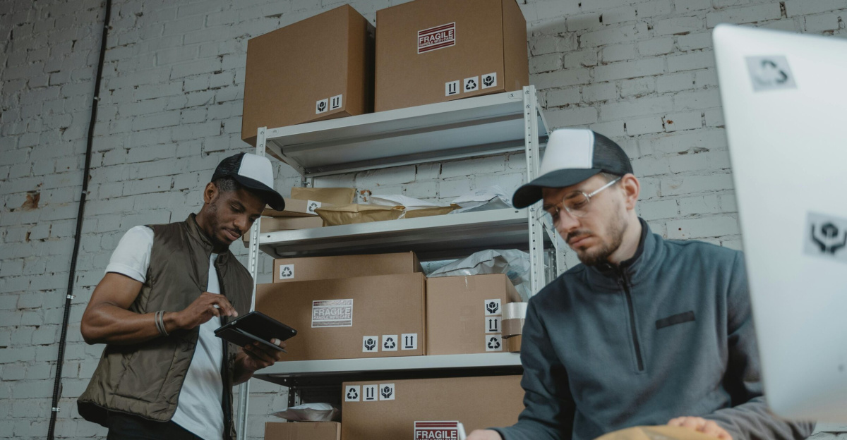 Two warehouse employees organizing and packing parcels for delivery in a modern indoor setting.