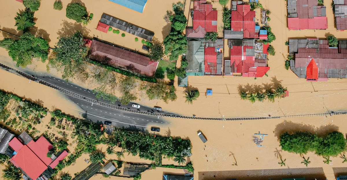 Aerial view showing significant flood damage in a residential neighborhood with inundated streets and homes.