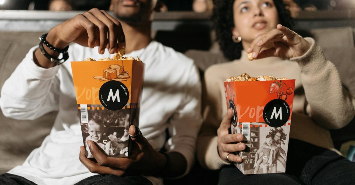 A couple enjoys popcorn while watching a movie in a theater