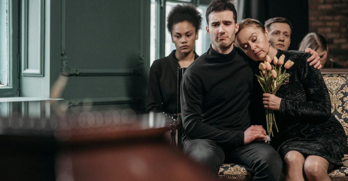 Family members in mourning sit together during a funeral expressing sorrow and support