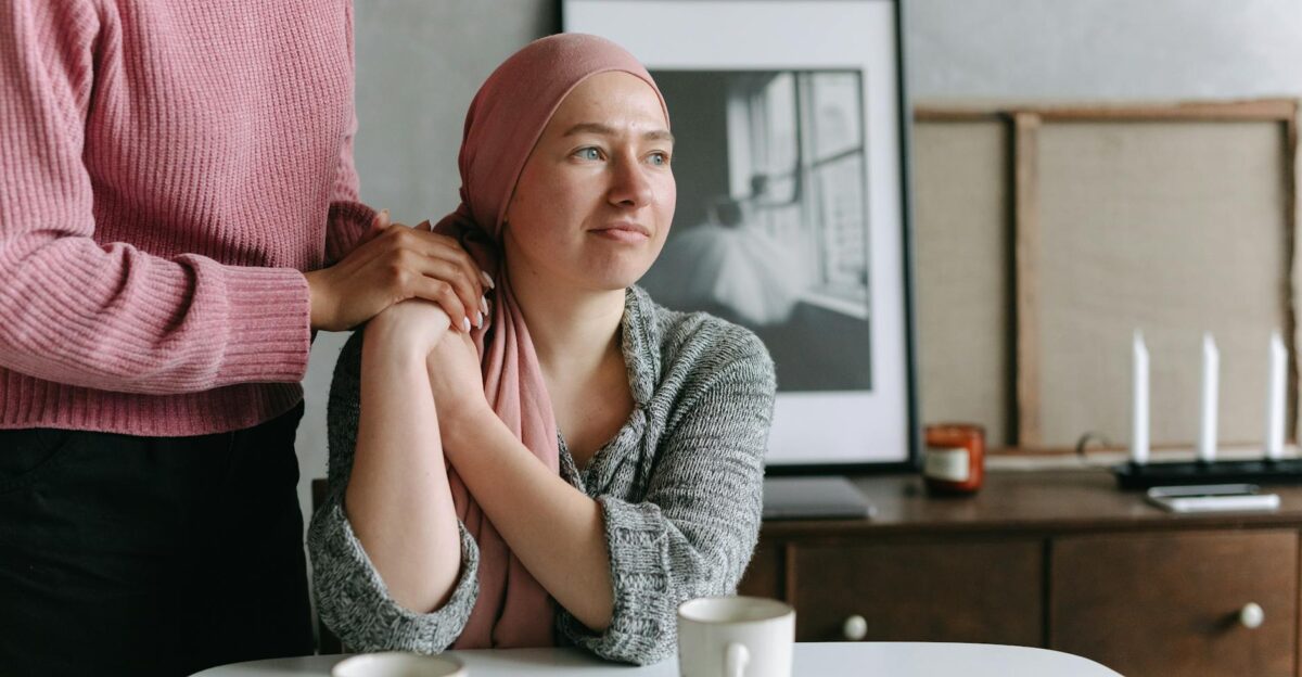 A supportive moment indoors featuring a cancer patient comforted by a friend conveying emotion and care