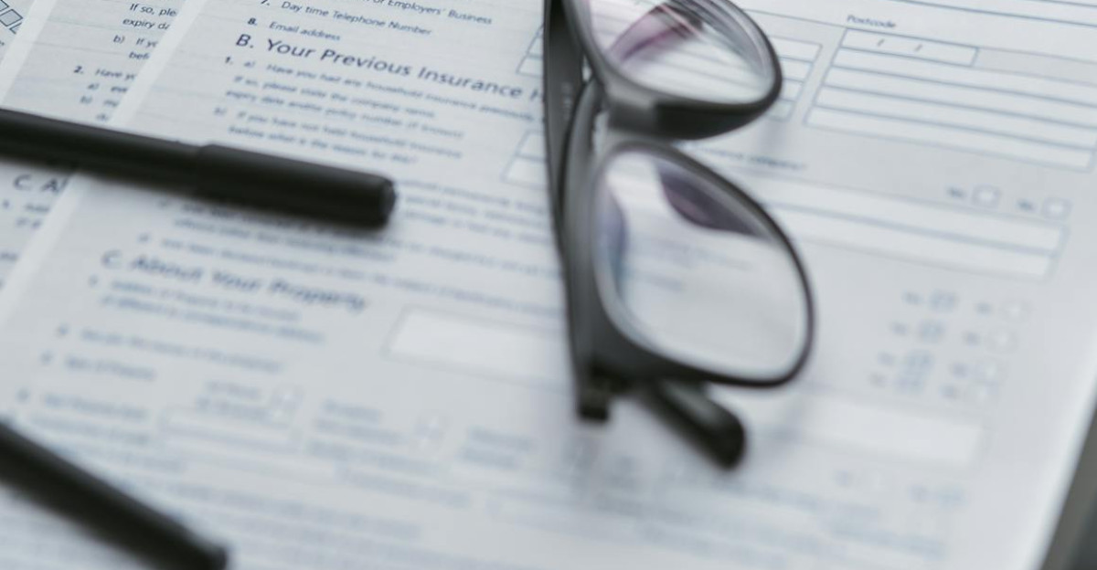 Close-up of home insurance policy document with glasses and laptop on a table