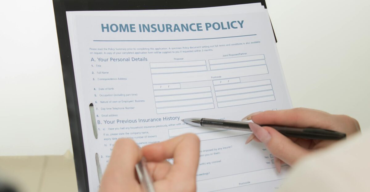 Hands holding pens filling out a home insurance policy document for coverage details