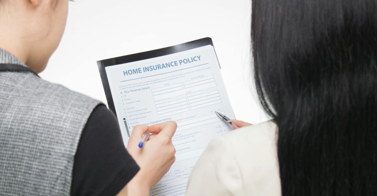 Two women examining home insurance policy form focused on details