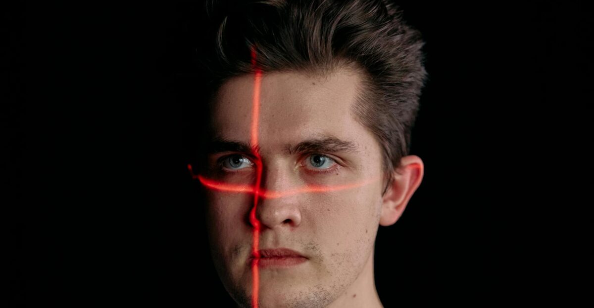 Conceptual portrait with laser scanning for facial recognition on plain black background
