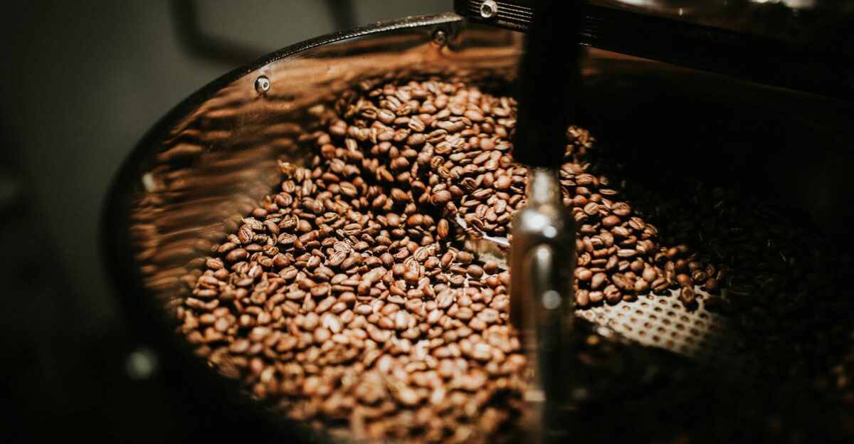 Close-up of freshly roasted coffee beans in a large industrial coffee roaster showcasing rich textures and warm tones