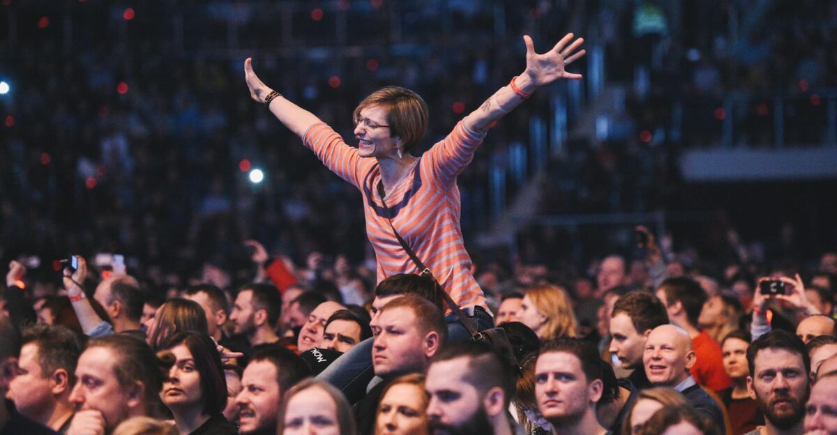 A woman joyfully cheers amidst a lively concert crowd exuding energy