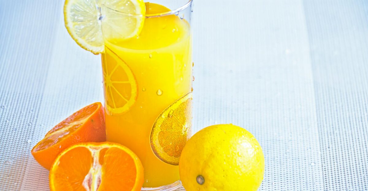 Vibrant citrus juice in a glass with fresh orange and lemon slices offering a refreshing taste of summer