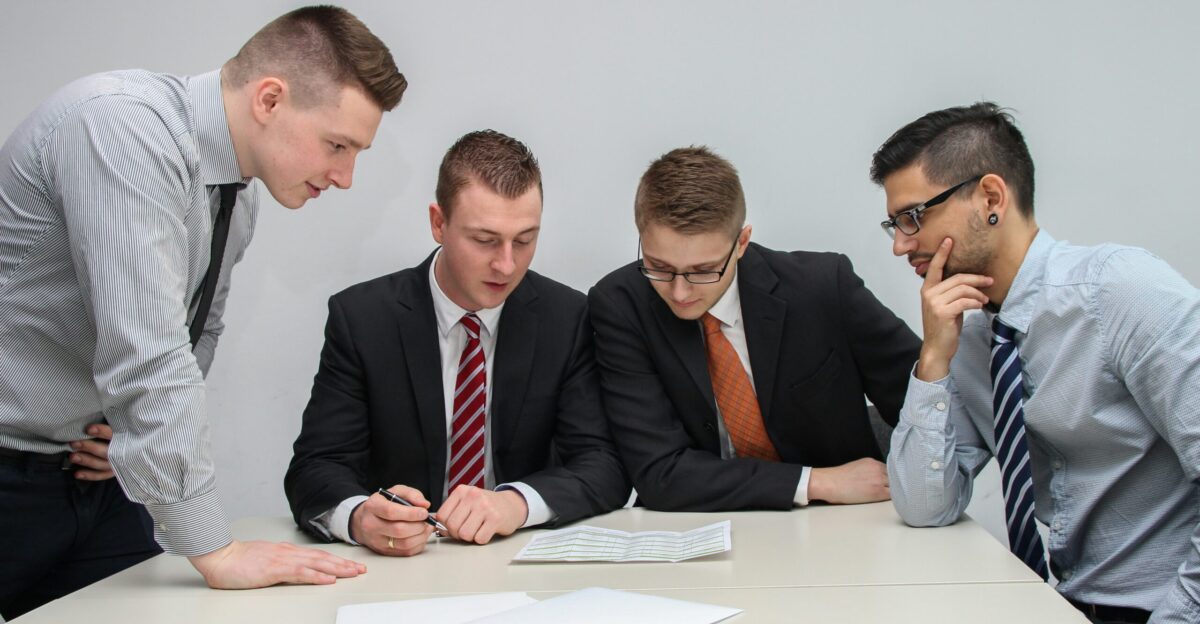 four men looking to the paper on table