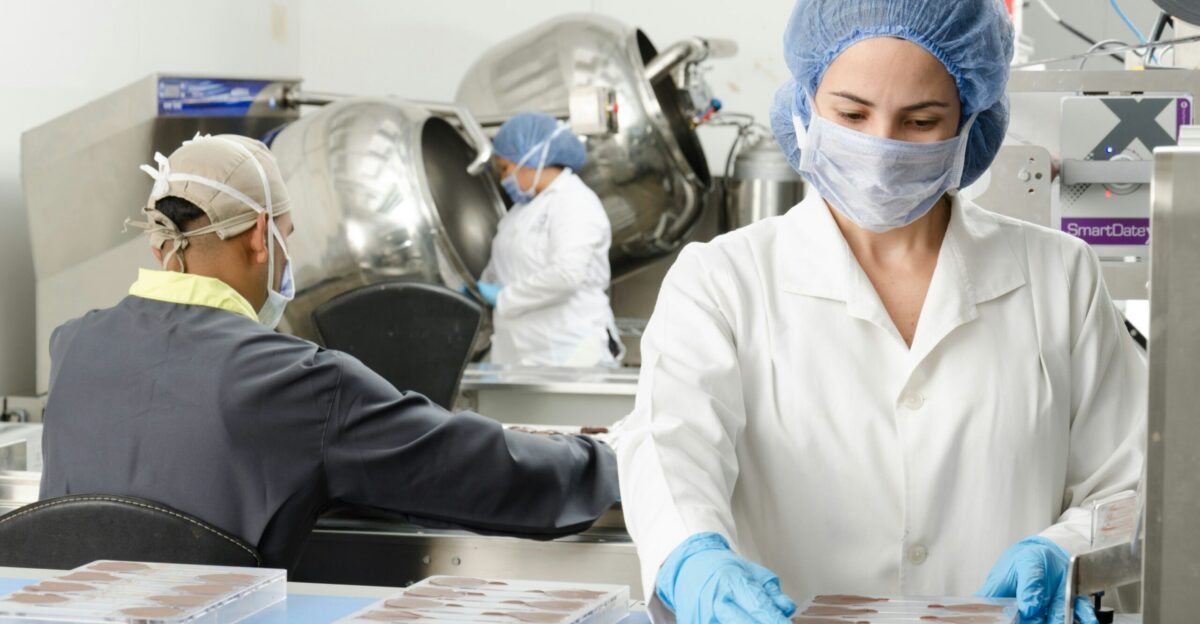 three people inside factory wearing masks and coats