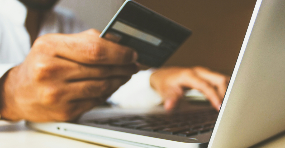 person using laptop computer holding card