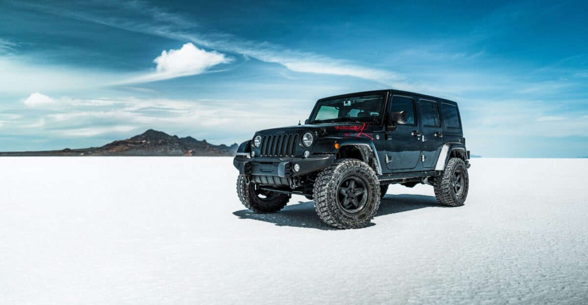 black jeep wrangler on snow covered field under blue sky during daytime