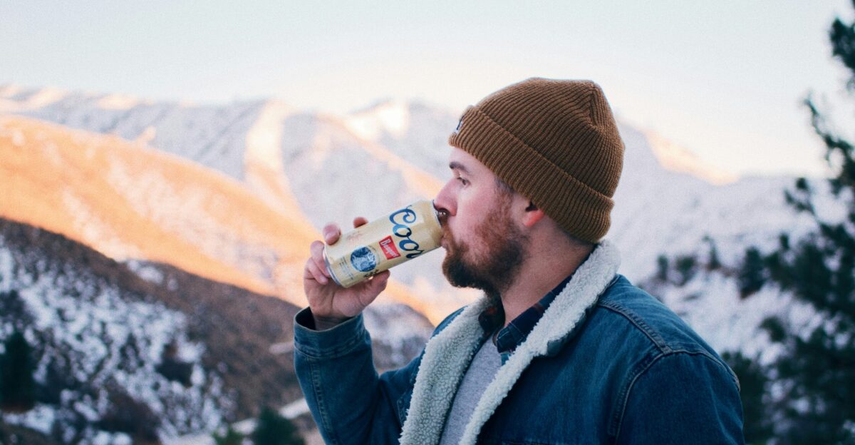 man in blue denim jacket drinking beer