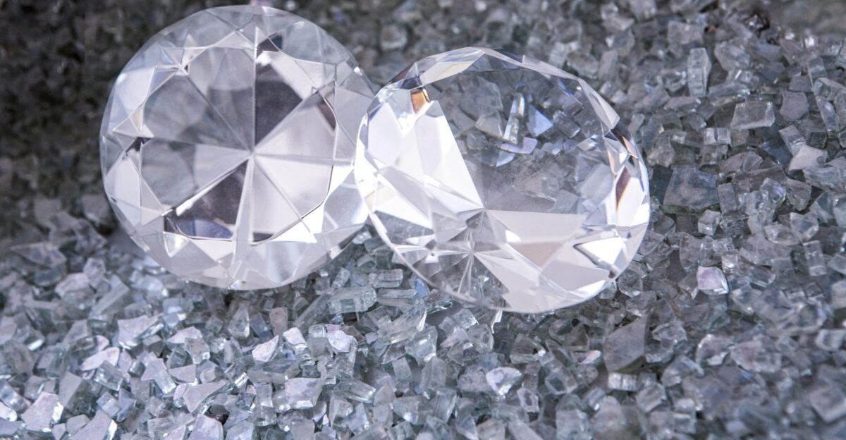 two diamonds sitting on top of a pile of crushed glass