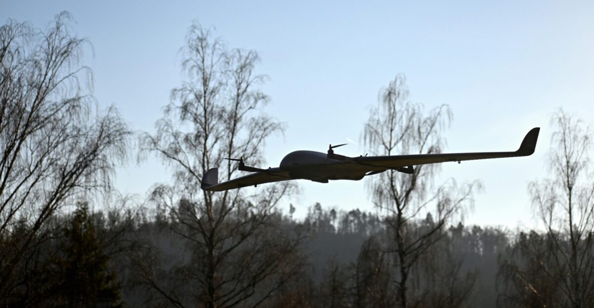 a plane flying over a forest with trees in the background