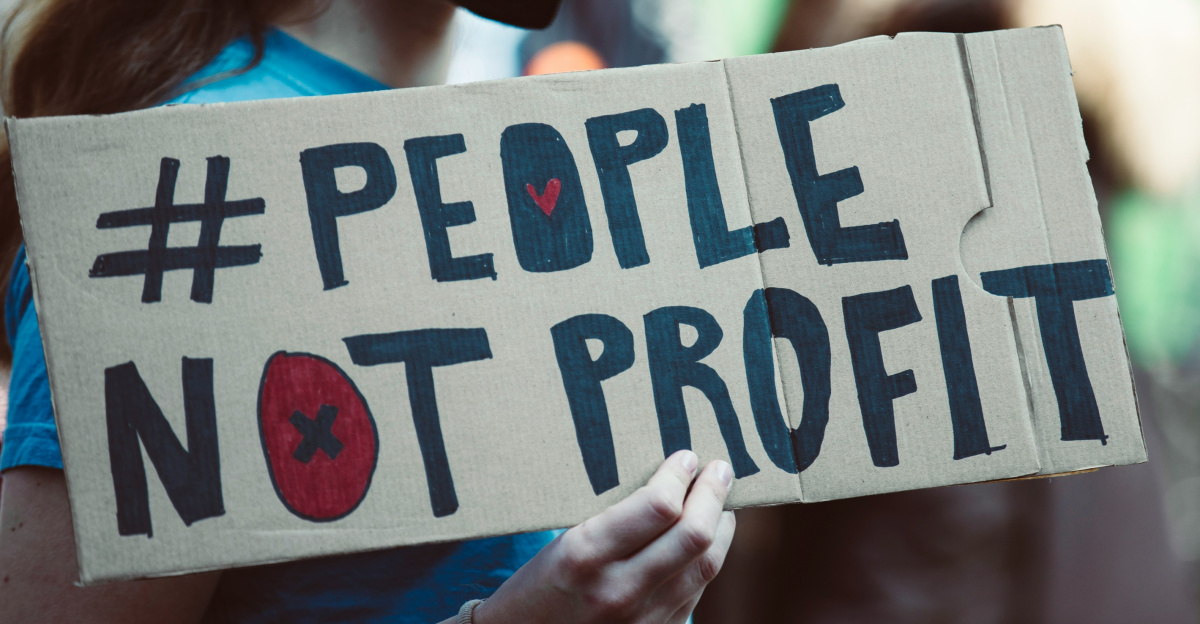 a woman holding a sign that says people not profits