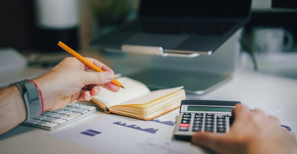 a person sitting at a desk with a calculator and a notebook
