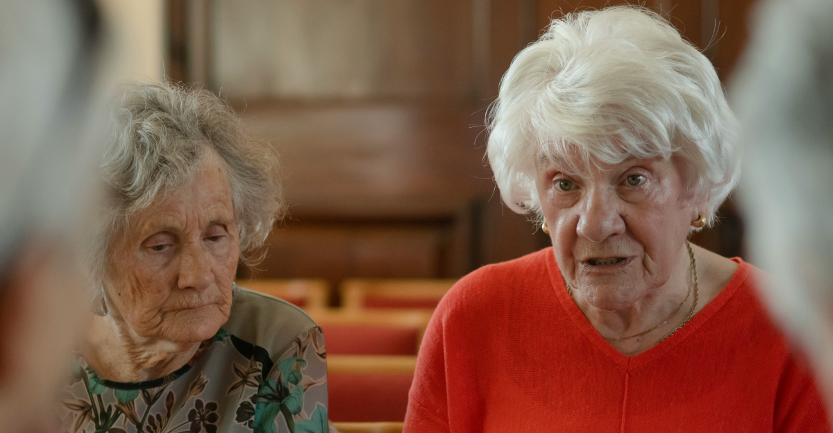Elderly women sit around a table, talking.