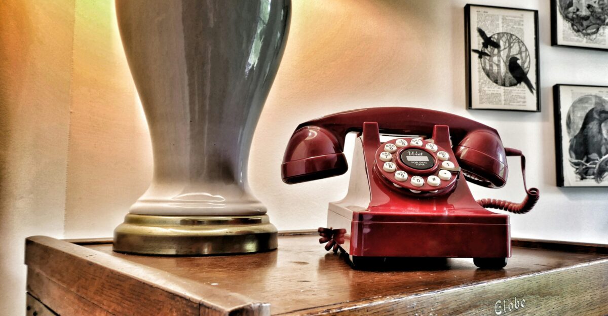 Vintage red rotary phone on wooden surface