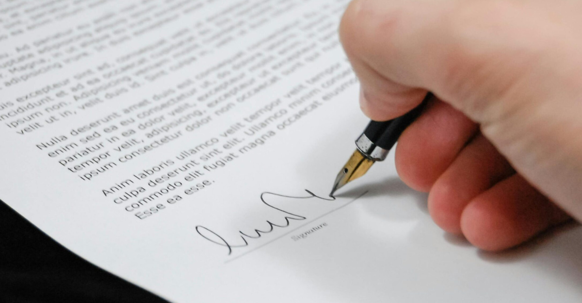 Close-up of a hand signing a legal document with a fountain pen, symbolizing signature and agreement.