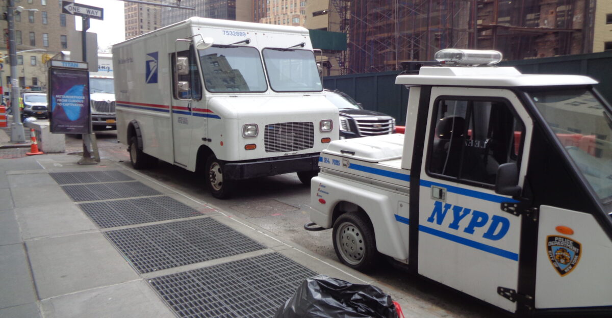 A USPS delivery truck and a three-wheeled NYPD car at Trinity Place north of Edgar Street across from the future 77 Greenwich Street in the Financial District Manhattan