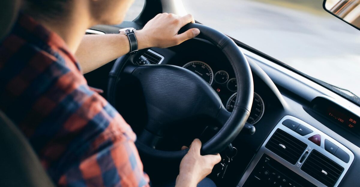 Close-up view of a man driving a modern car showing dashboard and steering details