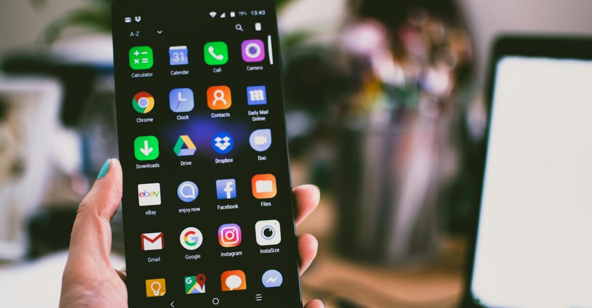 A close-up image of a person s hand holding a smartphone displaying various popular apps