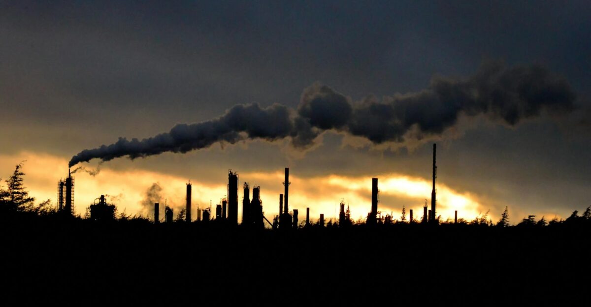 Silhouette of an industrial plant with smoke during a vibrant sunset