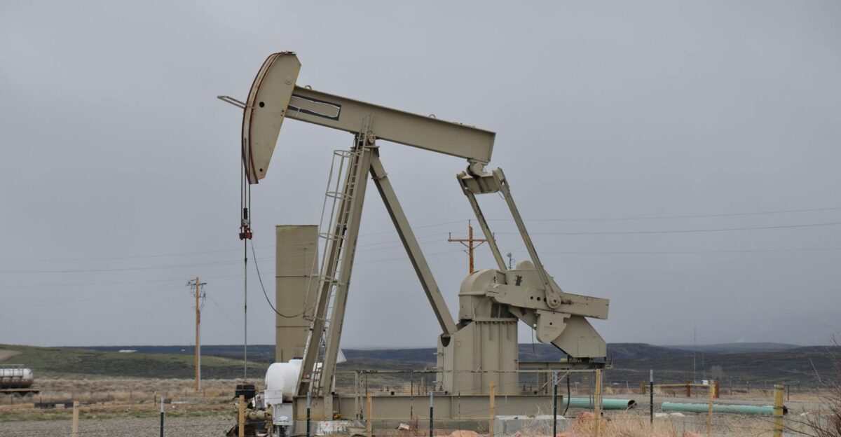 Oil pumpjack surrounded by barren landscape under overcast skies showcasing industrial machinery