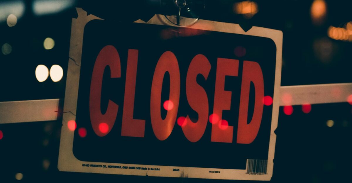 Moody image of a closed sign with bokeh lights conveying nighttime closure