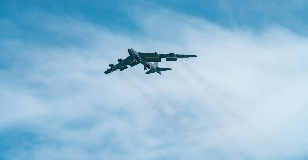 A B-52 Stratofortress aircraft soars through a clear blue sky on a sunny day