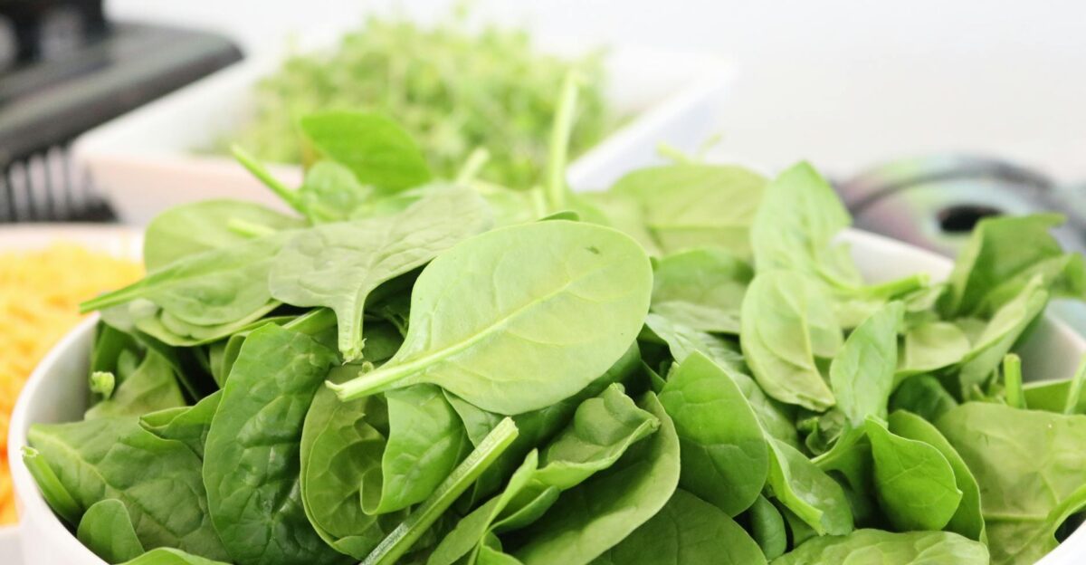 A close-up of fresh spinach leaves in a white bowl ideal for healthy salads