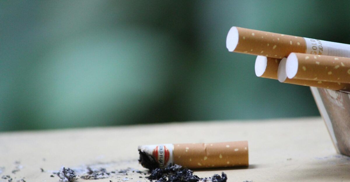 Cigarette with ashes on surface highlighting tobacco use and health risks