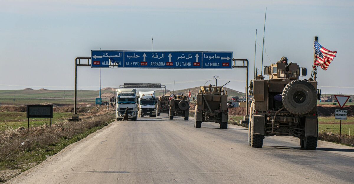 US military convoy travels on a highway in Al Hasakah Syria under blue skies