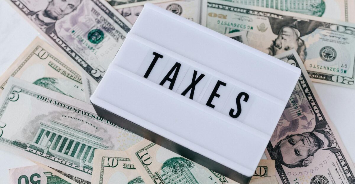 US dollar bills surrounding a sign showing TAXES Ideal for financial context