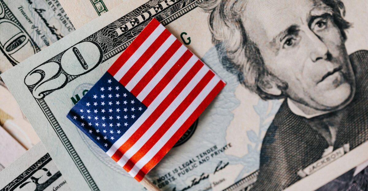 From above of small American flag placed on stack of 20 dollar bills as national currency for business financial operations