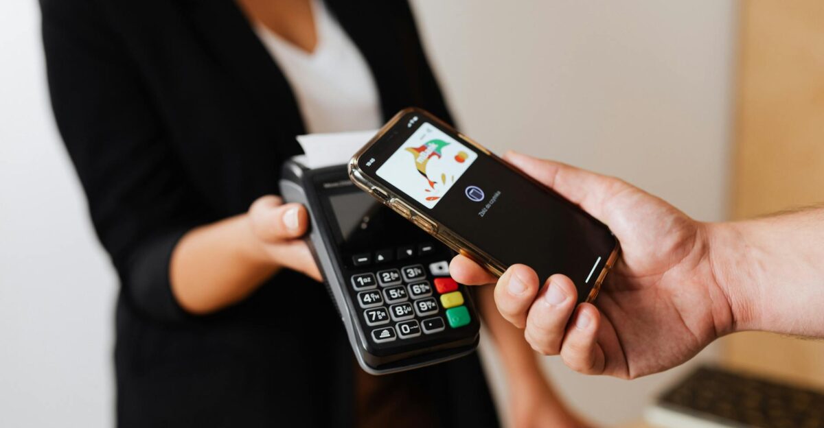 A person using a smartphone for contactless payment at a retail store counter