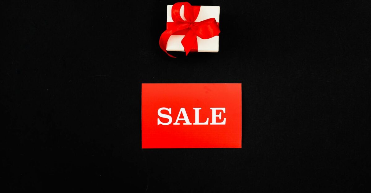 Top view of a red sale card and gift box with a ribbon on a black background Perfect for shopping promotions