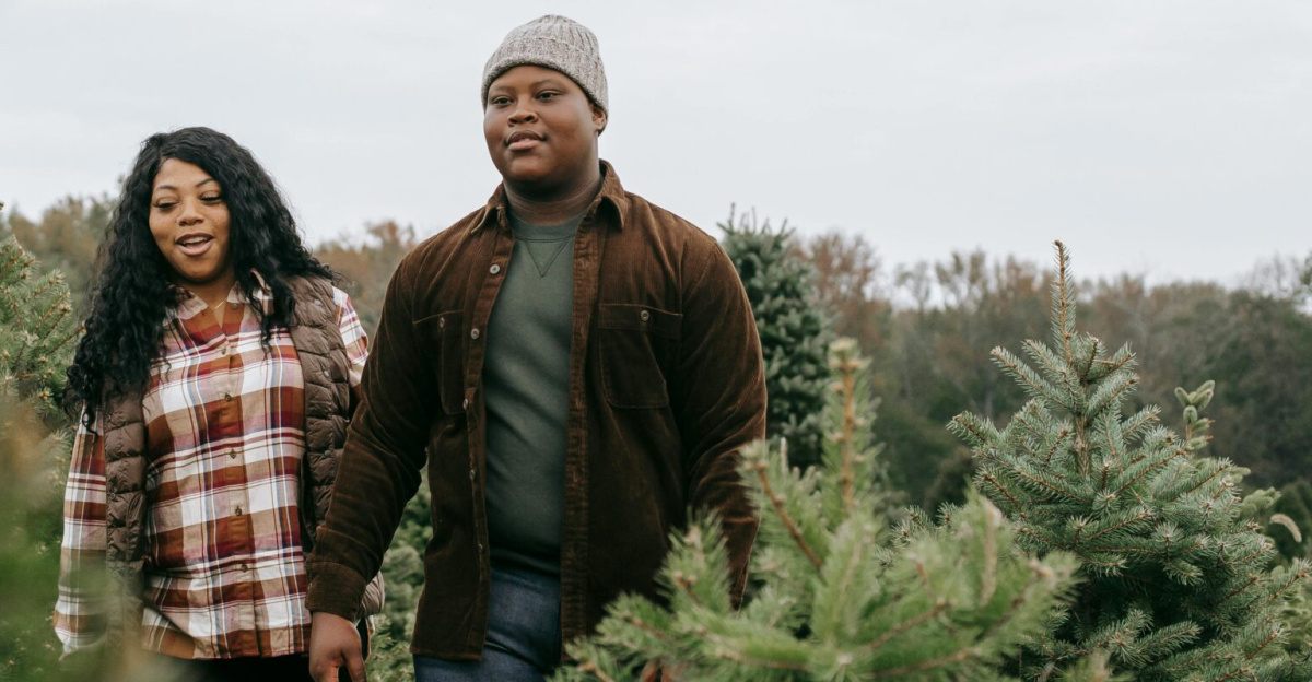 Positive African American mum talking to teen man while strolling on Christmas tree farm