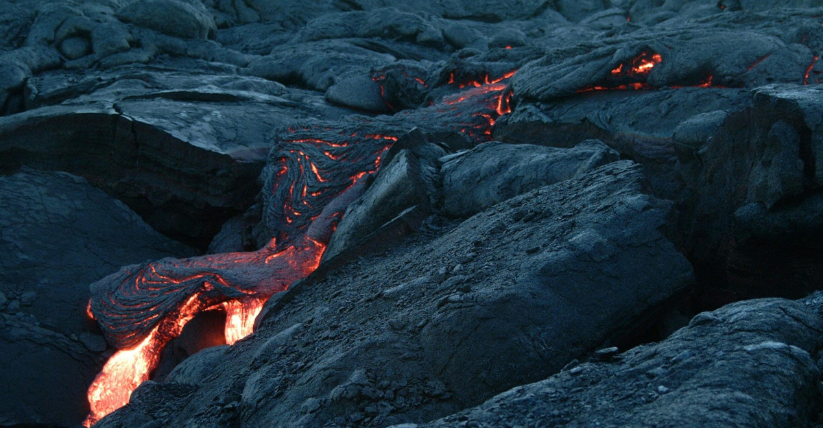 Captivating close-up of glowing molten lava flowing over solidified dark volcanic rocks.