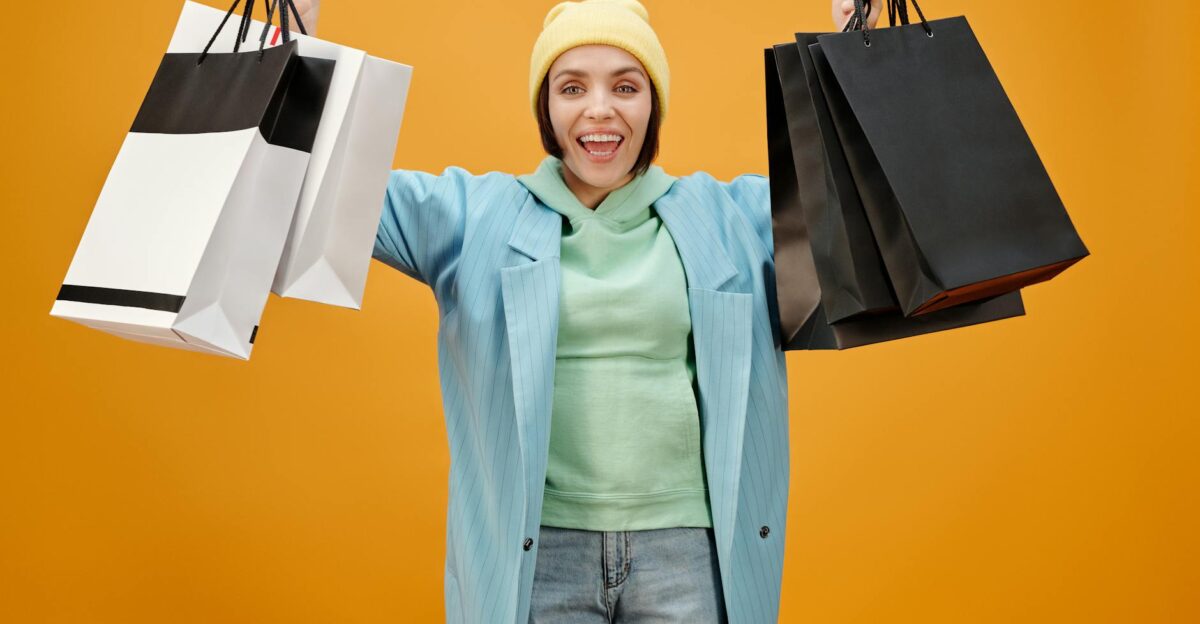 Smiling woman holding shopping bags against a bright yellow background perfect for e-commerce and marketing