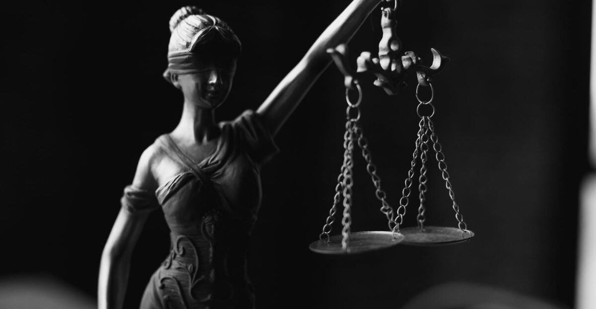 A close-up black and white photo of the Lady Justice figurine with scales