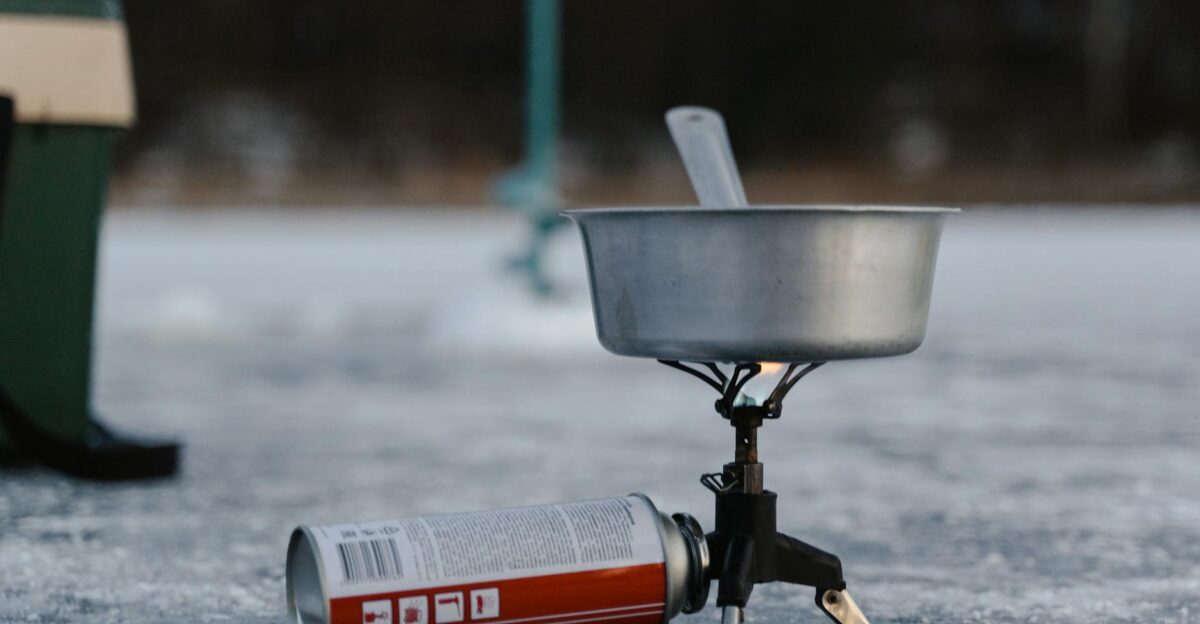 A camping stove setup on ice including a pot and butane canister for winter outdoor cooking