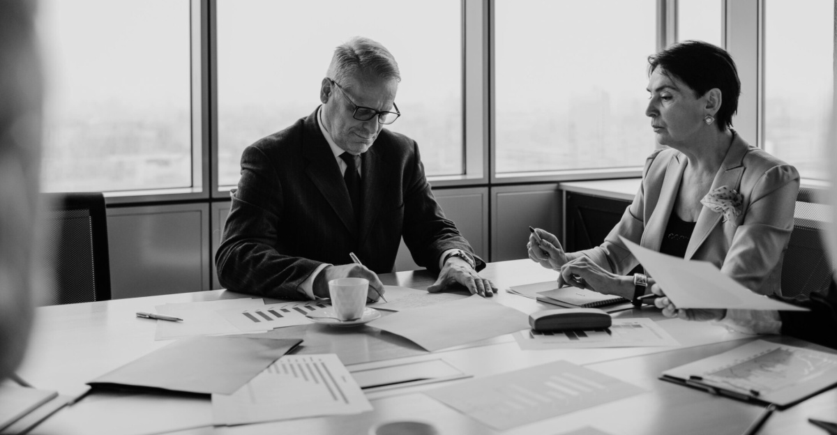 Black and white image of a business meeting with diverse professionals collaborating.