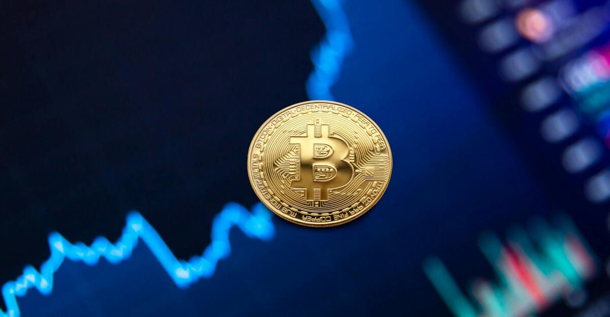 A gold Bitcoin coin against a backdrop of a digital financial chart symbolizing cryptocurrency trading
