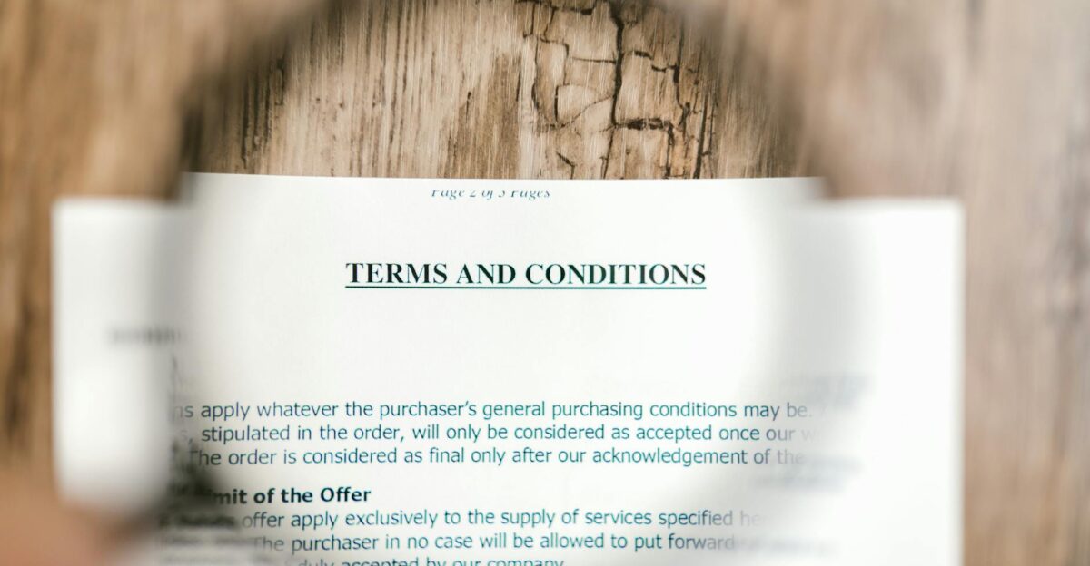 Magnifying glass focusing on terms and conditions document on wooden surface
