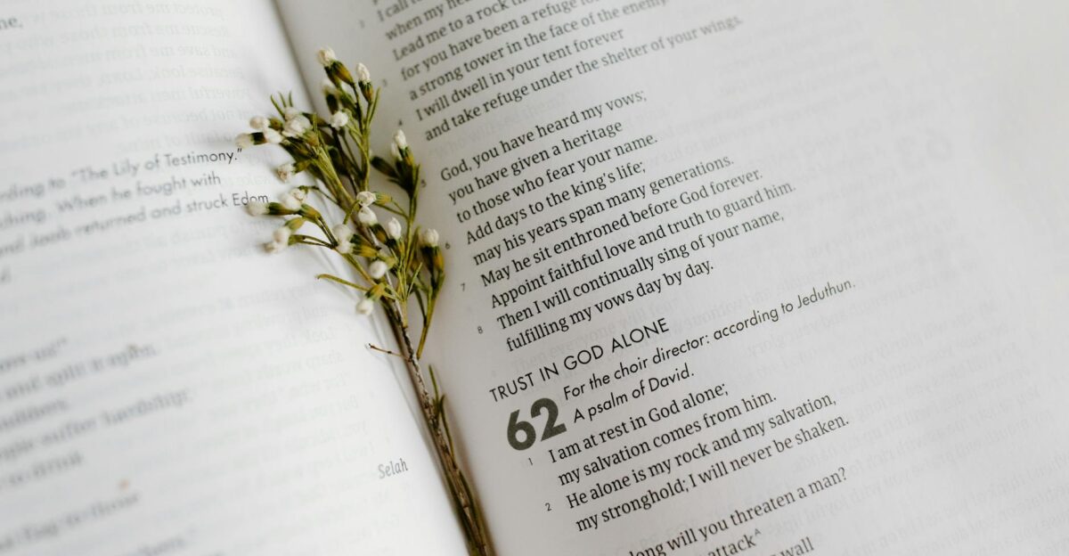A close-up of an open Bible page with scripture and delicate white flowers