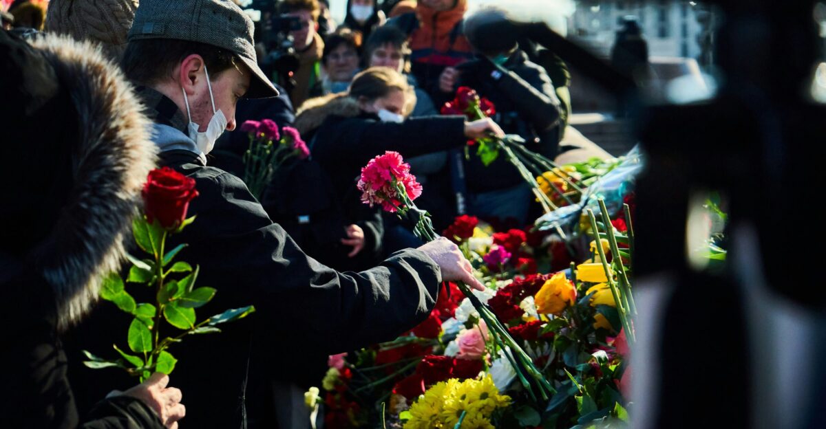 man in black suit holding bouquet of flowers
