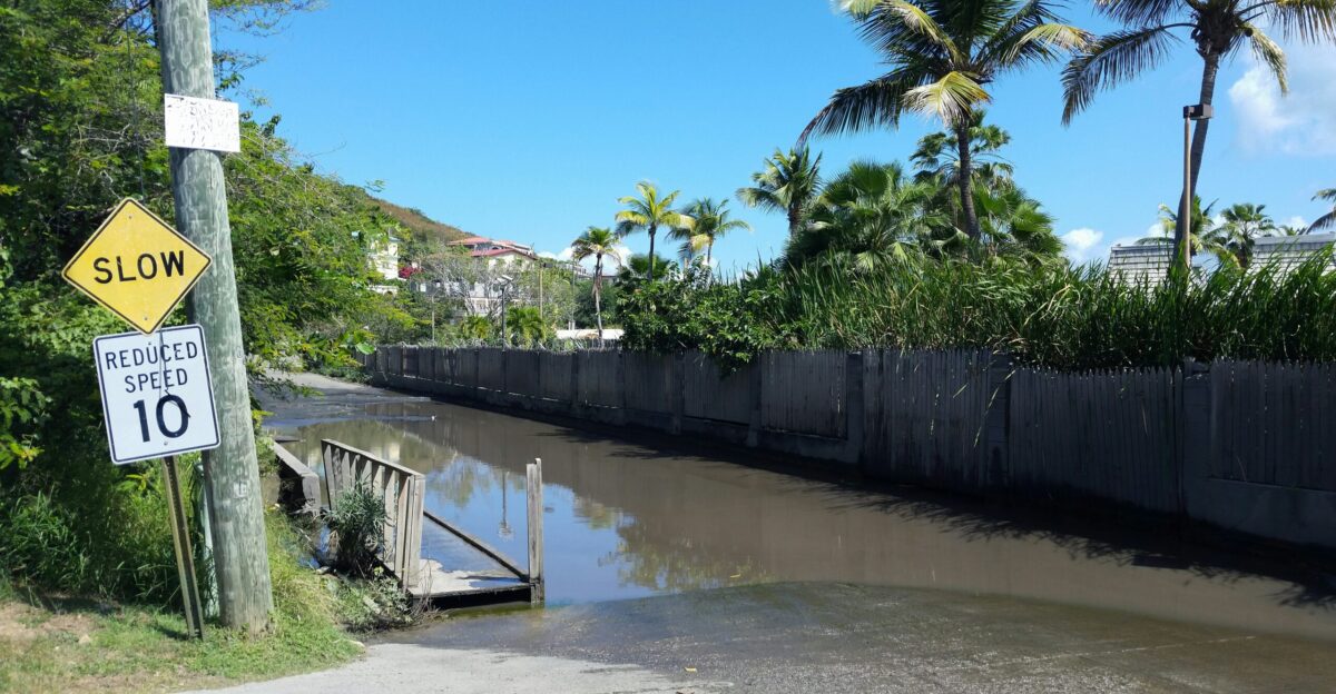 a flooded street next to a wooden fence